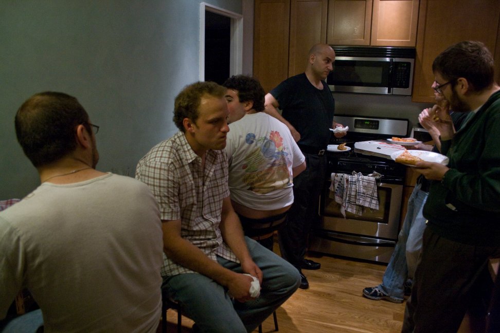 Cast and crew gather in a kitchen to prepare between takes.
